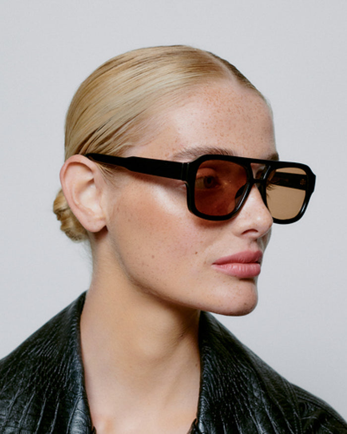 Person wearing black sunglasses with a plain background